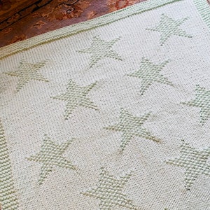 May include: A light green knitted baby blanket with a star pattern.