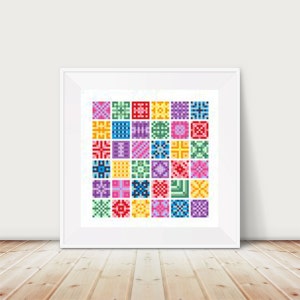May include: A framed artwork featuring a grid of colorful, pixelated squares. Each square displays a unique geometric pattern in shades of red, green, blue, yellow, purple, and pink. The artwork is displayed in a white frame against a white wall, resting on a wooden floor.