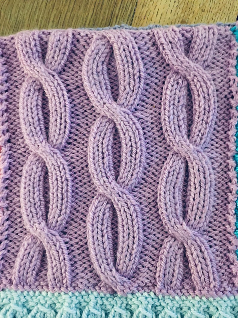 Peut inclure: Gros plan sur un tissu tricot&eacute; avec un motif de point de c&acirc;ble. Le tissu est de couleur violet clair.