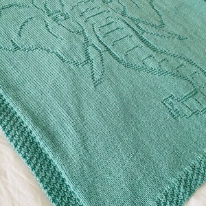 Pode incluir: Um cobertor de beb&eacute; de malha azul turquesa com um design de elefante.