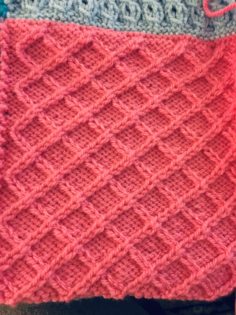 Peut inclure: Gros plan sur un tissu tricot&eacute; rose avec un motif en nid d'abeille.