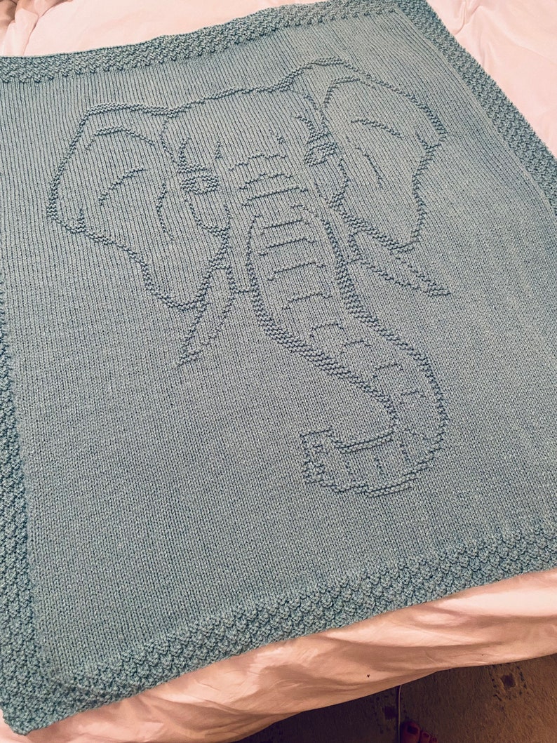 Pode incluir: Um cobertor de beb&eacute; azul claro de malha com um design de elefante.