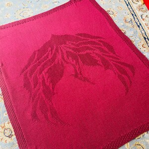 May include: A burgundy knitted throw blanket with a large, embroidered wing design.