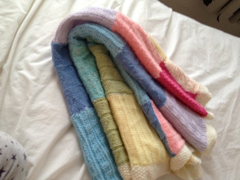 May include: A multi-colored knitted blanket with stripes of lavender, pink, yellow, green, and blue.