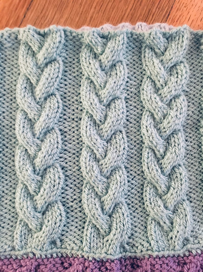Peut inclure: Gros plan sur un tissu tricot&eacute; bleu clair avec un motif en c&ocirc;tes. Le tissu a un aspect et un toucher doux et textur&eacute;.