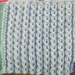 Peut inclure: Gros plan sur un tissu tricot&eacute; de couleur bleu clair avec un motif textur&eacute;. Le tissu est compos&eacute; de petites boucles rondes qui cr&eacute;ent une surface bomb&eacute;e et en relief.