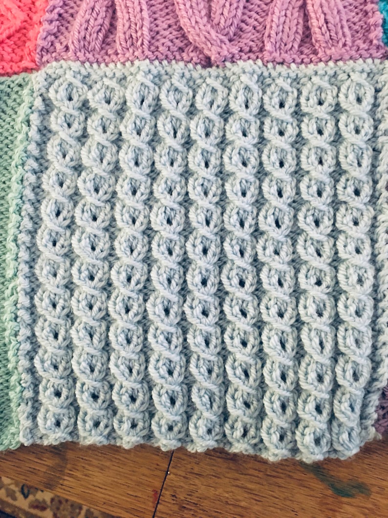 Peut inclure: Gros plan sur un tissu tricot&eacute; de couleur bleu clair avec un motif textur&eacute;. Le tissu est compos&eacute; de petites boucles rondes qui cr&eacute;ent une surface bomb&eacute;e et en relief.