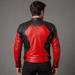 K&ouml;nnte beinhalten: Eine schwarz-rote Lederjacke mit Stehkragen, langen &Auml;rmeln mit Rei&szlig;verschlussb&uuml;ndchen und verstellbaren Seitengurten mit schwarzen Kunststoffschnallen. Das R&uuml;ckenteil zeigt ein markantes rotes X-f&ouml;rmiges Design auf einer schwarzen Lederbasis.