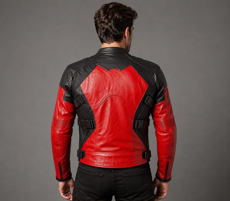 K&ouml;nnte beinhalten: Eine schwarz-rote Lederjacke mit Stehkragen, langen &Auml;rmeln mit Rei&szlig;verschlussb&uuml;ndchen und verstellbaren Seitengurten mit schwarzen Kunststoffschnallen. Das R&uuml;ckenteil zeigt ein markantes rotes X-f&ouml;rmiges Design auf einer schwarzen Lederbasis.