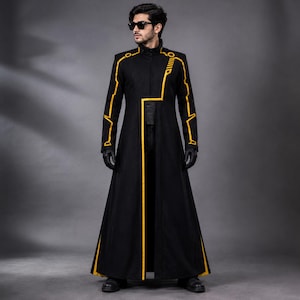 May include: A long black coat with gold trim and detailing. The coat has a high collar and a tailored design, with gold lines accenting the sleeves and front. The coat is worn with black gloves and sunglasses.