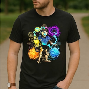May include: Black t-shirt featuring a colorful graphic of a mystical figure surrounded by energy orbs and a circular design with symbols. The artwork includes shades of blue, purple, yellow, and orange.