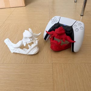 May include: A white and red decorative faceplate for a gaming controller. The white faceplate is on the left, and the red faceplate is on the right, attached to a white and black controller. The faceplates have a detailed, stylized design.
