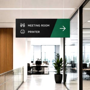 May include: A rectangular hanging sign with a black left section and a green right section. It features white icons for a meeting room and a printer, with the text MEETING ROOM and PRINTER, plus a white arrow pointing to the right side.