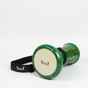 May include: A green darbuka drum with a cream drumhead and a black strap. The drum is decorated with gold accents and floral patterns. The drumhead features a graphic of stick figures.