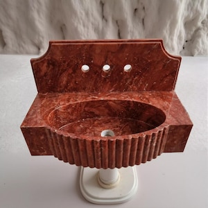 a red marble sink with a unique, ribbed design.