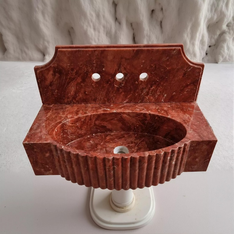 a red marble sink with a unique, ribbed design.