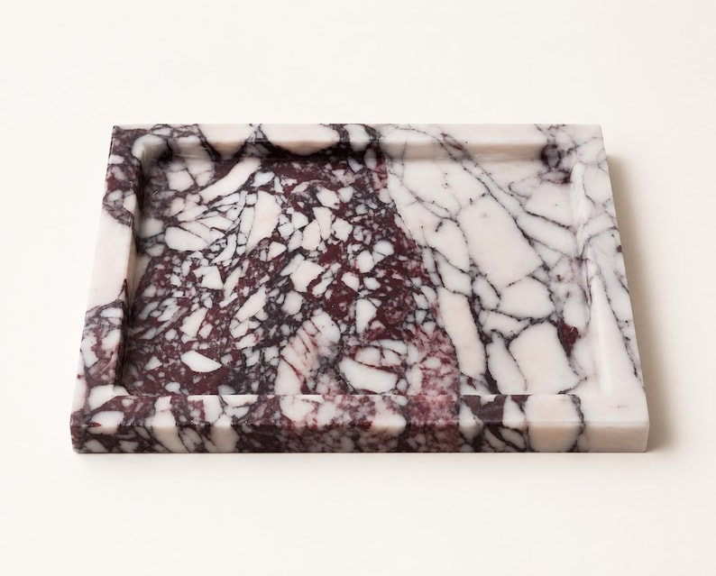 May include: A square tray crafted from polished stone featuring a distinct brecciated pattern. The surface displays a high-contrast mix of deep burgundy and stark white angular fragments, creating a complex, fractured appearance with raised edges.