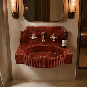 a bathroom with a red marble sink and a mirror above it. There is a bottle of soap on the sink.