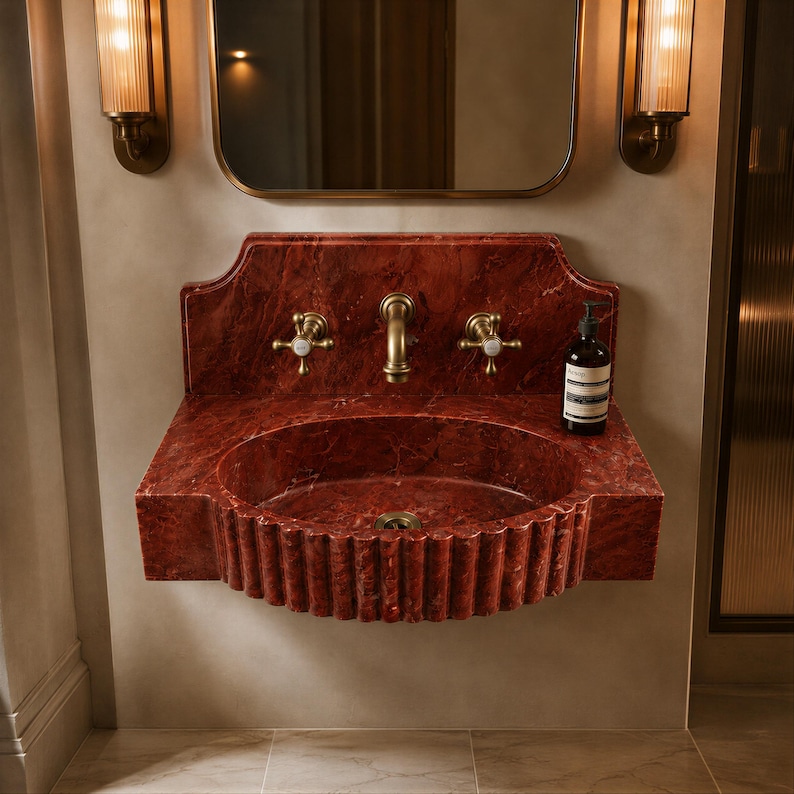 a bathroom with a red marble sink and a mirror above it. There is a bottle of soap on the sink.