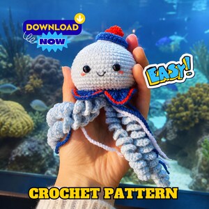 Peut inclure: Une méduse crochetée bleu clair avec un petit chapeau rouge, des yeux en perles noires et des tentacules bouclés. Le jouet présente un col à volants bleu et rouge. Le texte sur l'image inclut DOWNLOAD NOW, EASY! et CROCHET PATTERN en jaune.