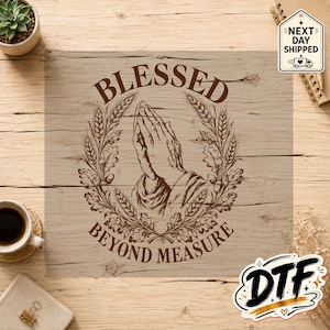 May include: A brown graphic print on a light wood grain background featuring praying hands centered within a circular wreath of wheat stalks and oak leaves. The text BLESSED is arched above the hands and BEYOND MEASURE is arched below.