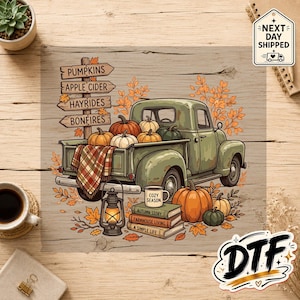 May include: A vintage green pickup truck illustration featuring a wooden signpost labeled PUMPKINS, APPLE CIDER, HAYRIDES, and BONFIRES. The truck bed holds pumpkins and a plaid blanket, with a lantern and books titled COZY SEASON, AUTUMN STORY, FARMHOUSE LIVING, and A SIMPLE LIFE nearby.