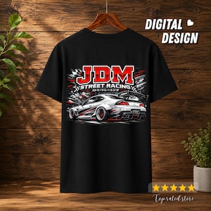 Puede incluir: Una camiseta negra con un estampado gráfico de un coche deportivo blanco con detalles en rojo. El texto JDM STREET RACING está impreso en rojo y blanco sobre el coche, acompañado de caracteres japoneses y un diseño de bandera a cuadros.
