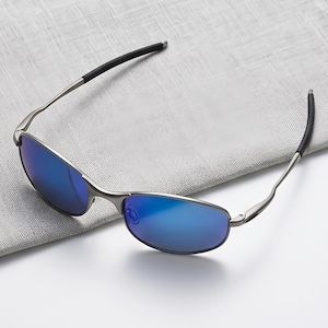 May include: Sunglasses with a thin, metallic silver frame and reflective blue lenses. The temples are slender and feature black rubberized tips for grip. The design is sleek and lightweight, showcasing a classic oval lens shape with a metallic bridge.