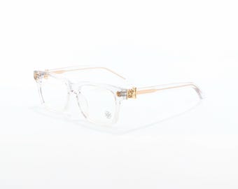 ゴールドの十字架のディテールがあしらわれた透明なスクエア型メガネ