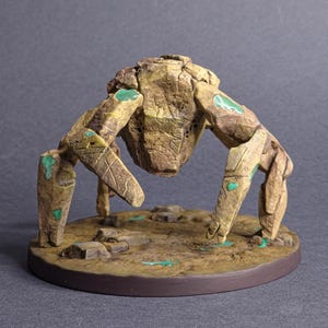 Könnte beinhalten: Detaillierte, handbemalte Figur einer steinernen Kreatur mit vier Beinen und einem zentralen Körper. Die Figur ist hauptsächlich beige mit grünen Akzenten und steht auf einem braunen Sockel mit strukturierter Oberfläche. Die Kreatur hat geschnitzte Details.