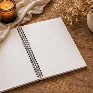 May include: An open spiral-bound notebook with white lined paper pages. The notebook features a black metal wire binding along the center fold, allowing the pages to lay flat. The paper is clean and blank, providing a surface for writing or drawing.