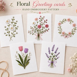 May include: Five white greeting cards featuring hand embroidery patterns of floral designs. The cards display a daisy sprig, a mixed wildflower bouquet, a circular floral wreath, two tulips with greenery, and a lavender sprig tied with a purple bow.