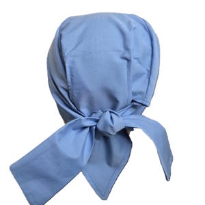 May include: A light blue bonnet-style head covering with a tied bow. The fabric is a solid, light blue color. The bonnet has a rounded shape with a seam down the center and ties at the nape of the neck.