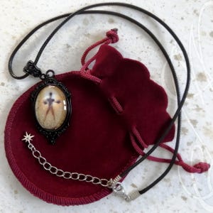 Puede incluir: Collar con colgante ovalado negro con dise&ntilde;o de silueta. El colgante est&aacute; engastado en un marco de filigrana negro y cuelga de un cord&oacute;n negro. Tambi&eacute;n se incluye una cadena plateada con un dije de estrella y una bolsa de terciopelo rojo.