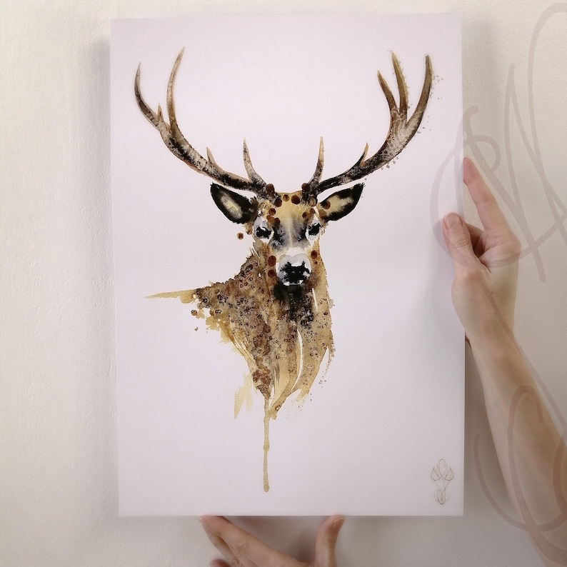 May include: A watercolour painting of a stag with large antlers. The artwork uses a brown and tan colour palette with a splattered effect, creating a textured appearance. The stag's head and neck are the focal point, set against a white background.