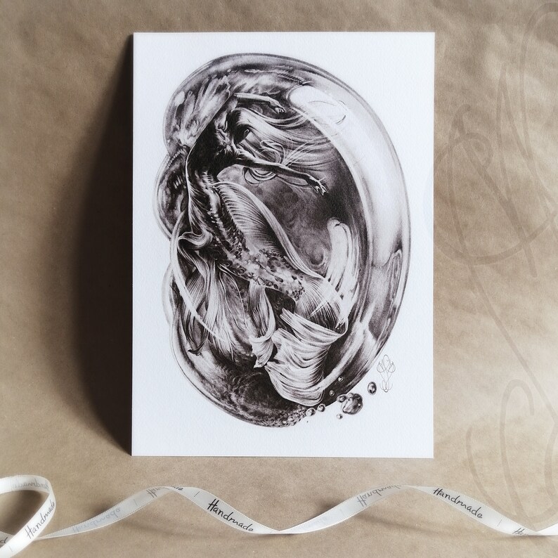 Pu&ograve; includere: Stampa artistica in bianco e nero di una sirena all'interno di una bolla. La sirena ha lunghi capelli fluenti e una coda di pesce dettagliata. L'opera d'arte &egrave; su una carta bianca, con un nastro con la scritta "Handmade".