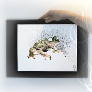 Puede incluir: Una pintura de acuarela de una rana en tonos verdes, negros y marrones, con un fondo blanco y un marco negro. La rana se representa de perfil con un patr&oacute;n moteado. Efectos de salpicaduras rodean la rana.