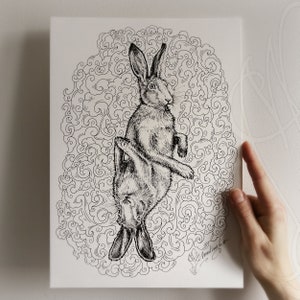 K&ouml;nnte beinhalten: Schwarz-Wei&szlig;-Illustration von zwei Hasen auf einer wei&szlig;en Leinwand. Die Hasen sind von einem wirbelnden, wolkenartigen Muster umgeben. Die Signatur des K&uuml;nstlers befindet sich unten rechts.