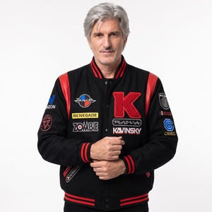 May include: A black varsity jacket with red leather sleeves and striped ribbed trim. The front features a large red letter K, the text Kavinsky, Plasma, Zombie, Renegade, and Zenith, along with various circular patches on the sleeves and chest.
