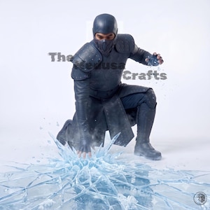 May include: A dark blue costume featuring a textured chest piece, shoulder guards with studs, a matching mask, and a long tunic. The outfit is worn in a kneeling position with one hand touching a surface that appears to be shattering like ice.