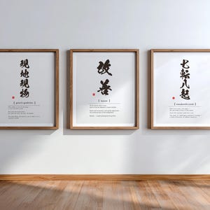Può includere: Tre stampe da parete incorniciate con calligrafia giapponese nera, romanizzazione fonetica e definizioni in inglese. Ogni stampa è racchiusa in una cornice di legno marrone chiaro e mostra caratteri kanji verticali con un timbro rosso.