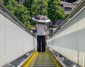 女性が傘をさしてエスカレーターに乗る写真、日本の都市ミニマリスト写真、白黒の都市風景（デジタルダウンロード）