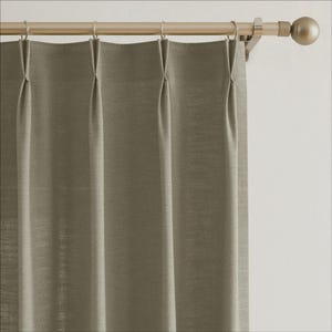 May include: A sage green curtain panel with a pleated design, hanging from a gold-coloured curtain rod. The rod has rings and a decorative finial. The fabric has a textured appearance. The curtain is approximately 150 cm wide.