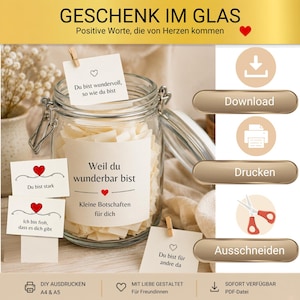 May include: A clear glass jar filled with small paper notes, featuring a label that reads 'Weil du wunderbar bist' and 'Kleine Botschaften für dich'. Several small cards with German text and red heart icons are displayed around the jar.