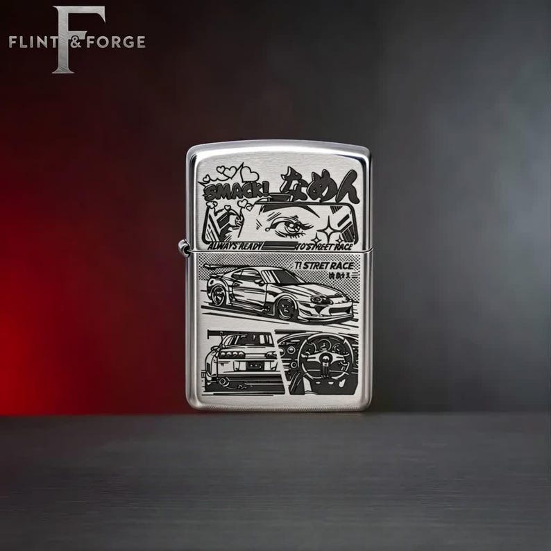 May include: A silver-colored lighter with a detailed graphic design. The design includes Japanese text, car illustrations, and the words "ALWAYS READY" and "TI STREET RACE". The lighter has a hinged lid and a flint wheel.