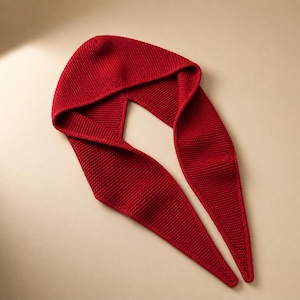 Può includere: Un cappuccio lavorato a maglia rosso vivo con lunghe estremità a sciarpa a punta. Il cappuccio è progettato per coprire la testa e il collo, con un motivo a maglia strutturato. Le estremità della sciarpa si estendono verso il basso, creando un accessorio unico ed elegante.