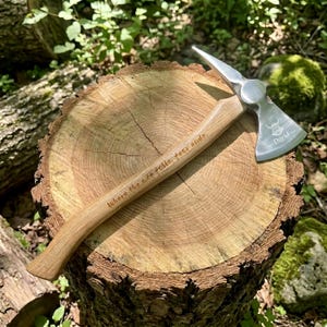 May include: A metal hatchet with a wooden handle featuring the engraved text 'Where the axe falls, fear ends.' The metal head displays a Viking helmet icon and the name 'David' etched into the surface, resting on a circular wooden log.