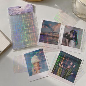 May include: A set of transparent adhesive sheets with a holographic grid pattern, packaged in a clear plastic sleeve labeled Fluorescent Magic. The sheets are layered over four square photographs depicting a sunset, a person with flowers, an ice cream cone, and pink tulips.