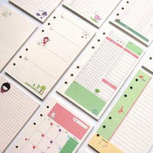 May include: A collection of loose-leaf planner pages featuring various layouts including weekly schedules, daily to-do lists, and monthly calendars. The pages are decorated with colorful illustrations of cartoon characters, trees, and small animals.