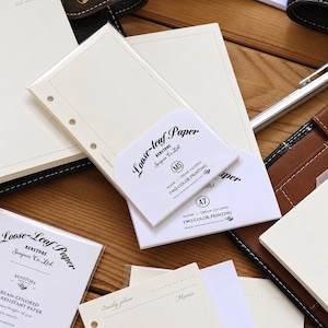 May include: A collection of cream-colored loose-leaf paper packs and inserts for planners. The packaging features black text including Loose-leaf Paper, Benstore, Senpoo Co. Ltd, M5, A7, and Two Color Printing. The paper sheets have pre-punched holes.
